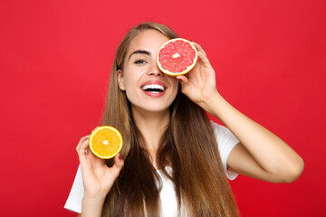 Young girl holding grapefruit and orange fruit on red background