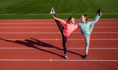 Keeping those muscles flexible. teen girls warming up on stadium. kids in sportswear stretching....