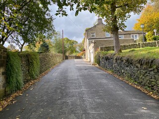 Climbing up, Butterworth Lane, with dry stone walls, and trees, on a cloudy autumn day in, Sowerby Bridge, Yorkshire, UK