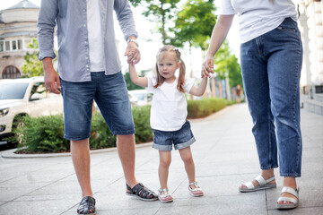 Three people, mother, father and daughter walking outdoor in the street of the city, people spending time with family together