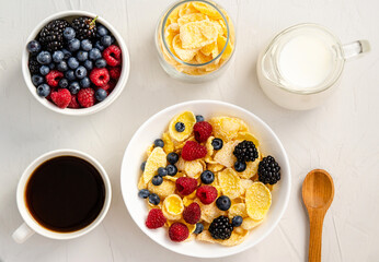 Cornflakes with milk and fresh berries on a white background.