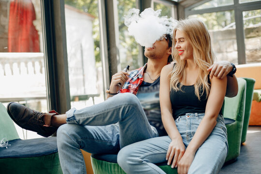 Stylish couple in a city. Two people use the electronic cigarette