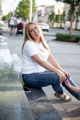 Beautiful overweight lady in white t-shirt and jeans, .walking in the street of the city and smiling.