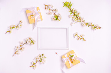 Gift boxes, blossoming cherry branches with a frame for text on a white background with copy space.