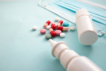 Close-up color tablets, pills, capsules, medical mask, and medical preparations lie on a blue background with copy spase