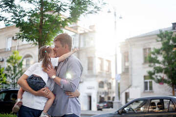 Fototapeta premium Three people, mother, father and daughter walking outdoor in the street of the city, people spending time with family together