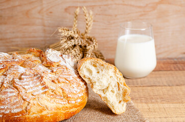 Broken loaf of wheat flour bread on a sackcloth on a wooden background.