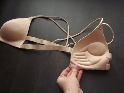 a woman's hand holds a beige bra. High quality photo