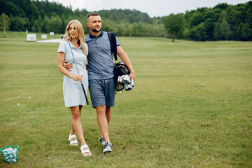 Couple in a golf course. Blonde in a sport clothes. Pair playing golf