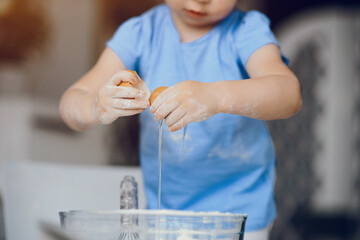 Child in a kitchen. Little girl with a dough. Kid in a blue t-shirt