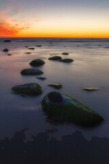 Beautiful colorful sunset over sea and boulders. Baltic sea shore, Estonia.