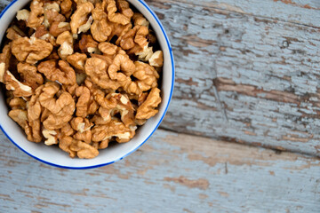 Walnuts. Walnut kernels. Clean organic walnuts. Nuts in the cup on vintage blue wooden background. Walnut tree fresh fall harvest.