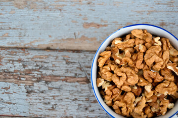 Walnuts. Walnut kernels. Clean organic walnuts. Nuts in the cup on vintage blue wooden background. Walnut tree fresh fall harvest.