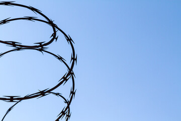 barbed razor wire against blue sky