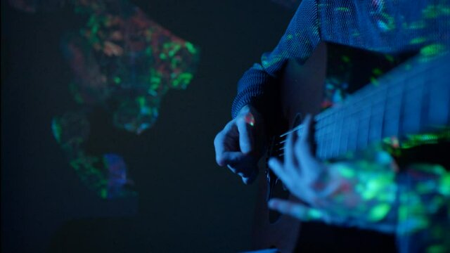 Musician playing acoustic guitar with abstract visuals
