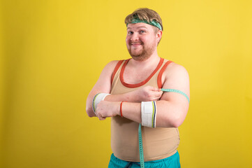 Funny overweight man flexing his muscle isolated on yellow background