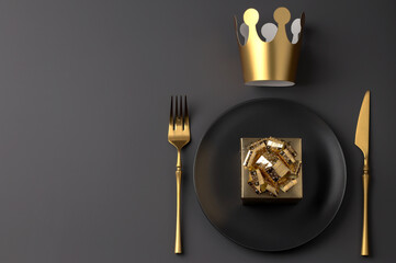 Creative table setting with gift box and crown, fork and knife in gold color on dark background. Valentine's Day, Wedding Day, Birthday, Women's Day and Mother's Day. Flat lay. Copy space