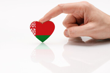 Love and respect Belarus. A man's hand holds a heart in the shape of the Belarus flag on a white...