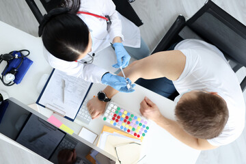 Doctor making injection of medicine into patients shoulder in laboratory top view