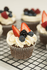 Cupcake decorado con betún y frutas frescas (fresa, blueberry)