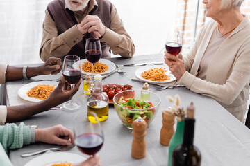 cropped view of multicultural and senior friends having delicious lunch together