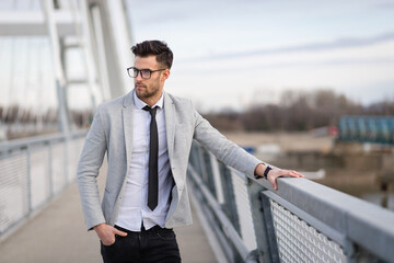 Young businessman standing on the bridge. Yuppie outdoors relaxing