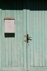 Old wooden door and rusty mailbox. Front view.