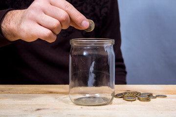 Fototapeta na wymiar throws a coin into a glass jar