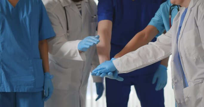 Cropped shot of medical team in gloves putting hands together