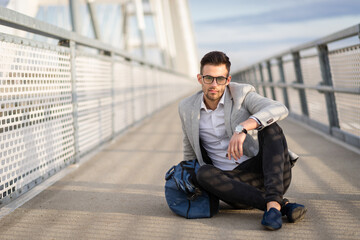 Hipster business casual male relaxing outdoors on the bridge. Yuppie or entrepreneur enjoying outside