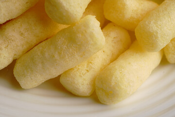 Corn sweet sticks very close on a white plate. Golden color.