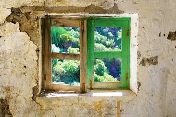 Old wooden window frame and wall in a ruin overlooking the nature in tenerife. The colors are brown green on the frame and beige on the wall. Outside Los gigantes, Tenerife / Spain