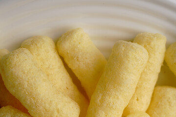 Corn sweet sticks very close on a white plate. Golden color.