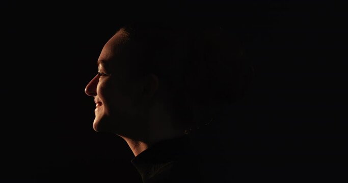 Woman silhouette. Female tenderness. Inner peace harmony. Romantic memory. Dark profile face shape of happy relaxed shy lady smiling enjoying moment isolated on black empty space background.