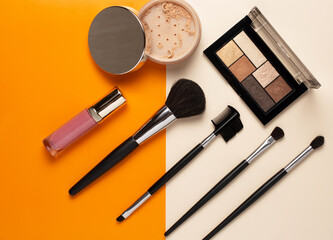 make up cosmetics, powder with various brushes and lipstick. colored background. flat lay.