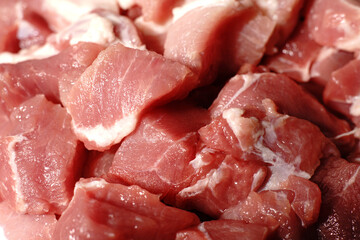 Raw pieces of red pork meat closeup. Finely chopped for cooking.