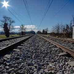 Fototapeta na wymiar Straight railway track perspective over stones on a solid blue sunny sky
