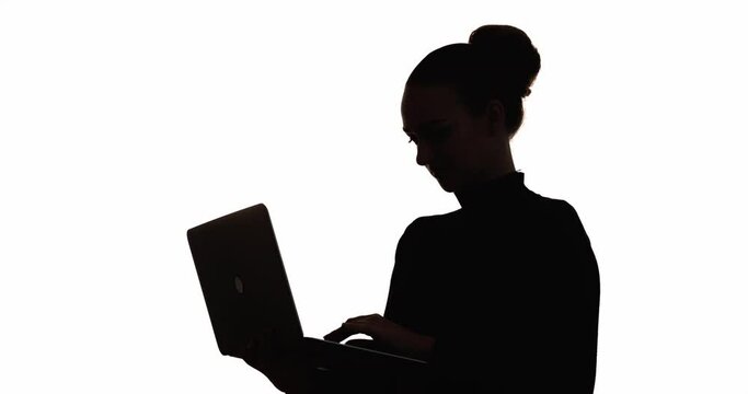Business woman silhouette. Remote job. Modern technology. Social media. Dark contrast outline of female freelancer working online using laptop typing isolated on white copy space background.