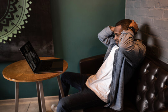 Frustrated african businessman sitting at desk holding his head reading bad awful negative news, fired from work. Dismissal notice, financial problem debt notice from bank, unpaid invoice concept.