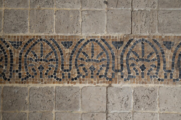 Mosaic texture made of natural sandstone. Closeup on a small square stone pavement background.