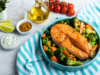 fried baked fish steak salmon, trout with broccoli and carrots on a plate