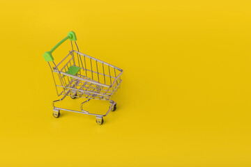Shopping cart on trendy illuminating yellow color background.