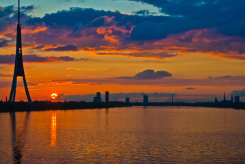 sunset. in the photo, the clouds are illuminated by the evening sun,in the foreground is a river, in the background is a city