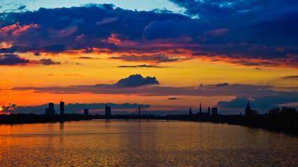 sunset. in the photo, the clouds are illuminated by the evening sun,in the foreground is a river, in the background is a city
