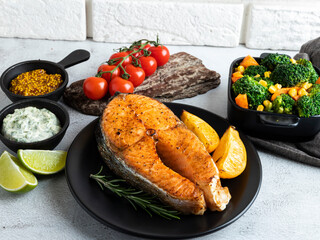 fried, baked fish steak salmon, trout with broccoli and carrots, lemon on a plate