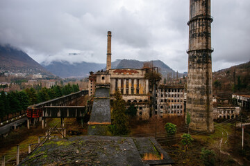 Fototapeta na wymiar Overgrown ruins of industrial building. Abandoned, destroyed by war power plant in Tkvarcheli Tquarhcal, Abkhazia, Georgia