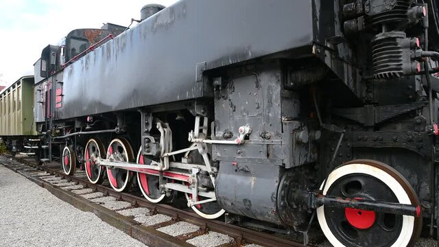 Old museum steam train on tracks. Locomotive details of gear wheels. Black vintage train on station in small town Naklo, Slovenia. Right pan, wide angle
