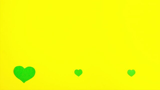 Stop motion animation of tree green paper hearts which change size at the bottom on yellow background Saint Patrick's Day 17 march traditional celebration holiday and good luck concept copy space