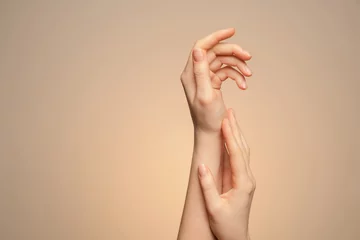 A woman's hands close up, on a beige background.