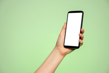 Fototapeta na wymiar Smartphone upright with a blank screen in a woman's hand on a green background.